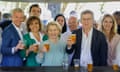 Ursula von der Leyen and fellow politicians hold up plastic glasses of beer as they pose for a picture
