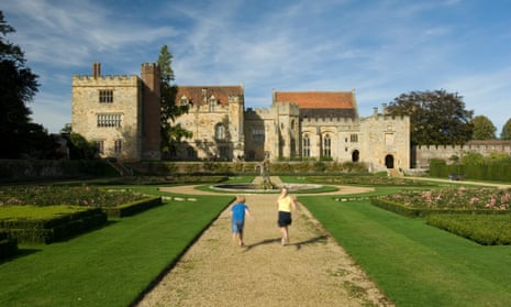 A young boy and girl walking through formal mediaeval gardens towards Penshurst Place in Kent.