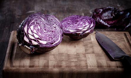 A red cabbage sliced in half on a chopping board.