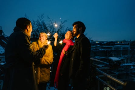 Four young adults on a terrace with sparklers.