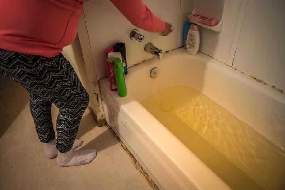 Tara Sakanee runs a bath at her home in Neskantaga. She says the water is usually varying degrees of yellow in colour and complains of itching and dry skin after showers.