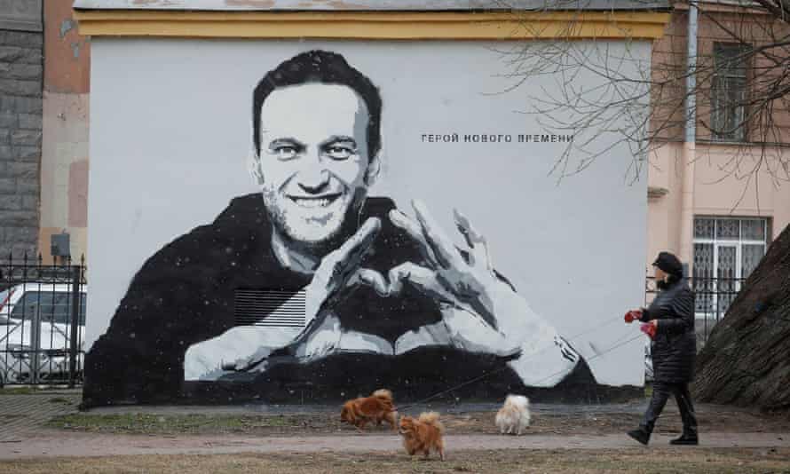 A woman walks her dogs in Saint Petersburg earlier this week in front of an image of Alexei Navalny. The text reads: ‘The hero of the new age’.