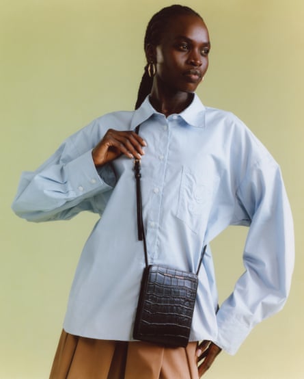 A model wears a blue shirt with a tan skirt and croc leather cross-body bag