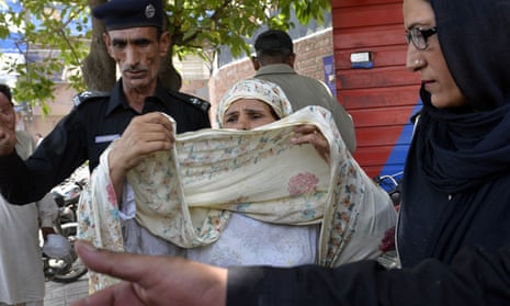 Pakistani police escort Perveen Bibi, who allegedly killed her own daughter by burning her alive after she married the man of her choice, into court in Lahore. 
