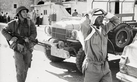An Israeli soldier marches a captured Jordanian soldier through the streets of Bethlehem.