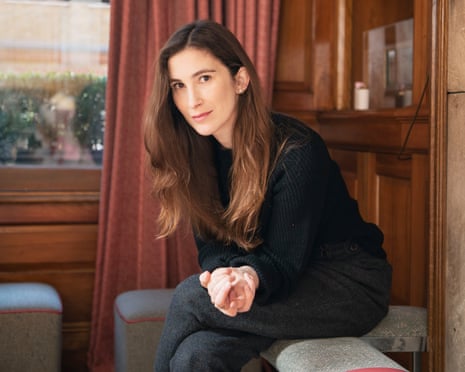 Portrait photo of Katherine Rundell sitting beside a fireplace