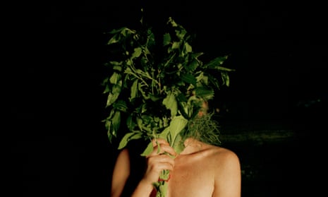Woman in sauna with her face obscured by leaves.