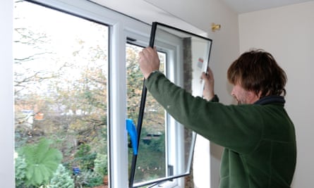 A man fitting double-glazing to a window.