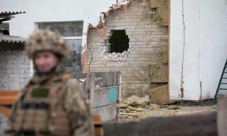 A Ukrainian soldier stands next to the damaged wall after the reported shelling of a kindergarten.