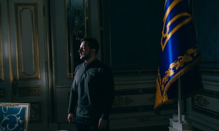 Zelenskyy stands near a flag