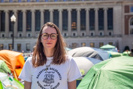 woman stands in front of an encampment of tents in front of a grand building