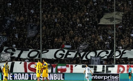PAOK fans rise a banner that reads “STOP GENOCIDE – SHOW ISRAEL THE RED CARD” during their Europa League match against Maccabi Tel Aviv