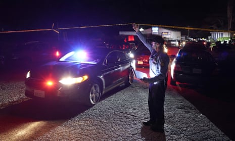 A San Mateo County sheriff deputy lifts up police tape for an exiting police car at the scene of a shooting on January 23, 2023 in Half Moon Bay, California.