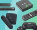 Various TV streaming devices and remotes arranged on a gridded surface, including boxes and controllers.