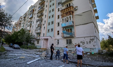 Locals and a policeman stand in front of a damaged residential building after a missile strike hit the Piatykhatky neighborhood of Kharkiv, northeastern Ukraine, 18 July 2022. According to the head of the Kharkiv regional state administration Oleg Synegubov, military strikes hit a Kharkiv district at night damaging only civil infrastructure with no casualties.