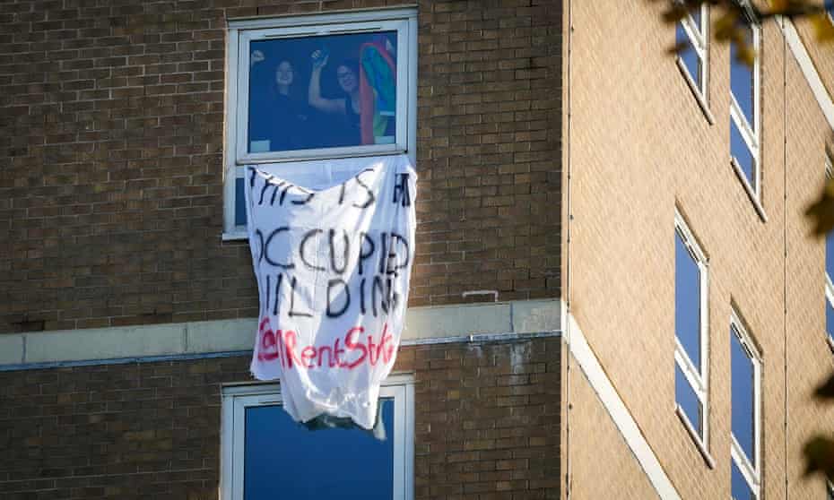 Manchester University students wave from the window of an accommodation tower block that they occupied in protest in November.