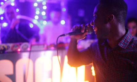 Man holds a microphone while performing on stage at Hip Hop Karaoke.