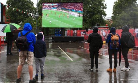 Cricket fans watch the England v Haiti FIFA Women's World Cup match in the rain on the big screen at Old Trafford.