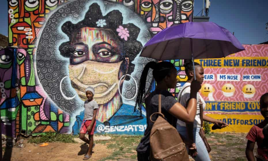 Residents in Soweto, Johannesburg, walk in front of graffiti educating about the dangers of the coronavirus.