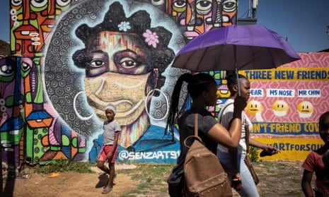 People walk past a Covid mural in South Africa of a woman wearing a face mask