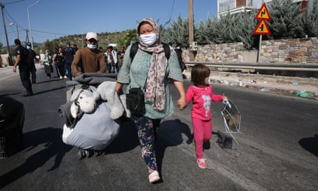 Refugees with their belongings near the burnt remains of Moria refugee camp on Lesbos. 