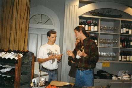 Gavin Newsom in his 20s in conversation with Billy Getty in a smart room surrounded by stacks of wine bottles