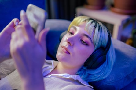 Teenage girl standing next to neon light and listening to music