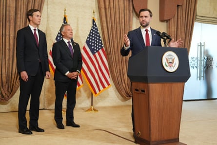 Three men in suits stand in front of two US flags