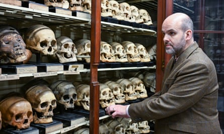 A man inspects rows of skulls.