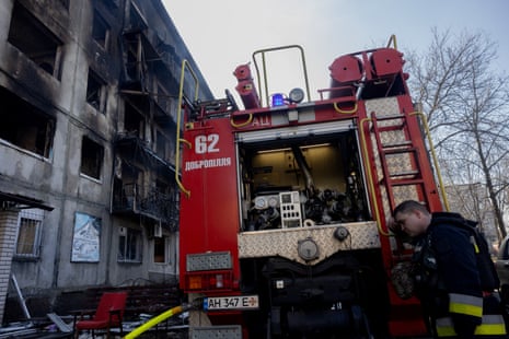 A firefighter leans on a fire truck near a damaged residential building after a strike in Dobropillia, Donetsk region, killed at least 14 people.