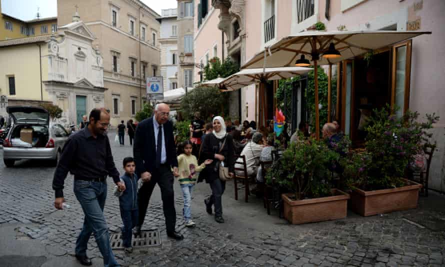 A Syrian family walks with a member of the Sant’Egidio Roman Catholic charity