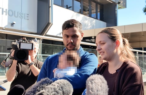 A young couple with a baby outside court