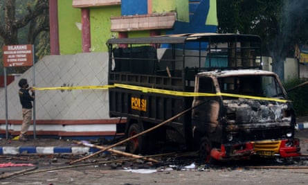 Police set up a cordon around a burnt-out vehicle outside the stadium after the riot