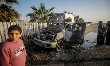 People stand near a destroyed car of the NGO World Central Kitchen (WCK) along Al Rashid road in the southern Gaza Strip.