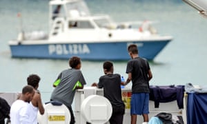 Migrants gather on the deck of the Italian coastguard vessel Diciotti in the Sicilian port of Catania, as they wait to disembark