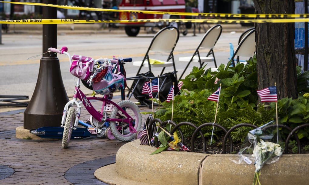 Flowers sit on a curb near a child's bicycle as members of the FBI's Evidence Response Team Unit investigate in downtown Highland Park, one day after a gunman killed seven people and wounded dozens more.