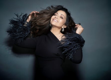 A woman of colour wearing a floaty black dress and smiling