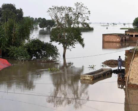 Flooding in a rural area in Punjab, Pakistan, with a lone man standing outside a flooded building