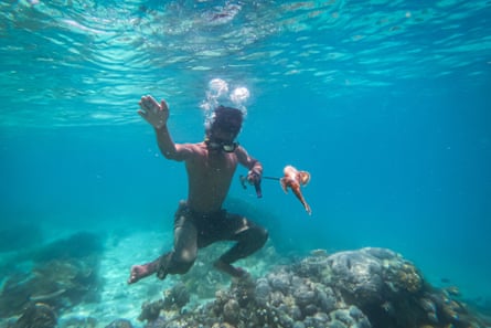 A Bajau boy catching a fish underwater with a spear.