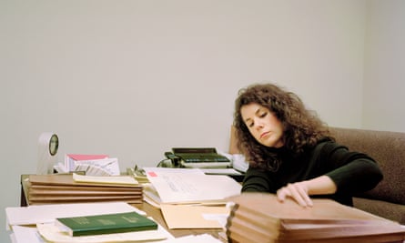 Woman sitting at a desk with lots of folders on it
