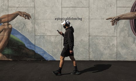 A man wearing a mask walks past street art in South Melbourne advocating social distancing
