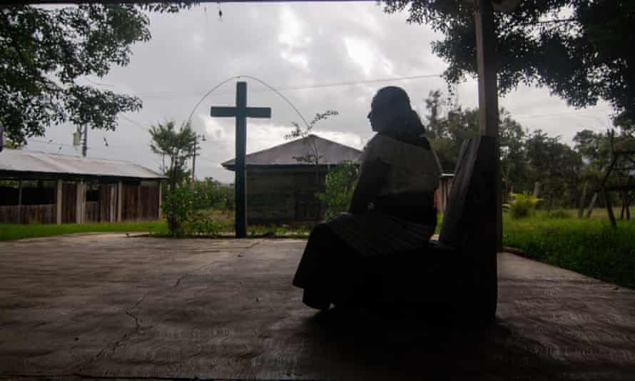 Indigenous woman pictured in silhouette before a large cross