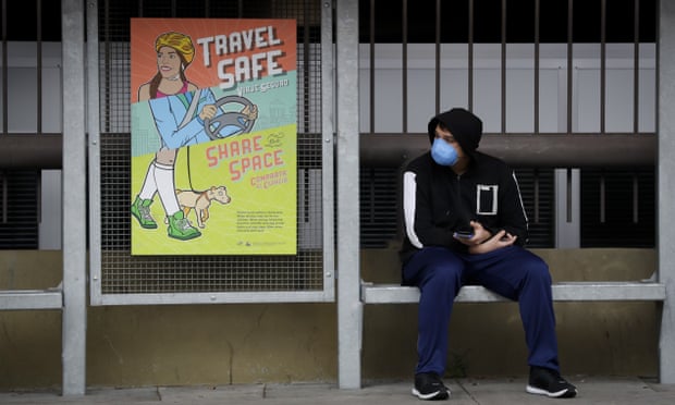 A bus rider wearing a face mask waits at a stop on 16 March 2020.