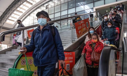 Pasajeros en una escalera mecánica en una estación de tren en Wuhan.