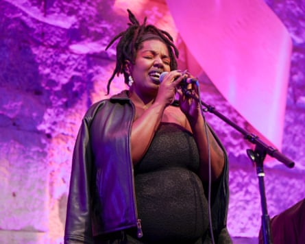 KeiyaA on stage in a black dress under purple lighting.
