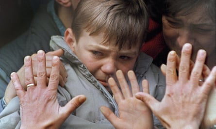A father’s hands press against the window of a bus carrying his son and wife to safety from the besieged city of Sarajevo in 1992