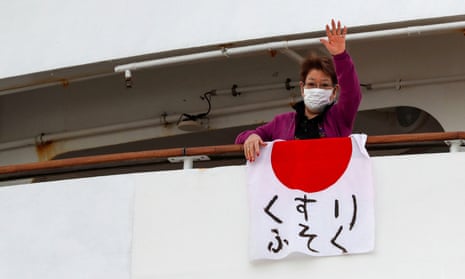 A woman waves after hanging a Japanese flag that reads “shortage of medicine” on the cruise ship Diamond Princess, where 61 people have tested positive for coronavirus.