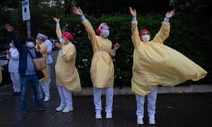 Heathcare workers wearing face masks and protective suits as they battle coronavirus acknowledge applause outside the Hospital de Barcelona on April 13, 2020.