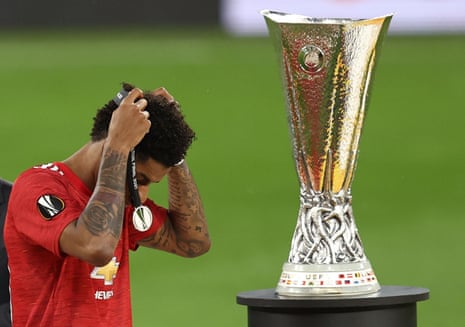 Manchester United’s Marcus Rashford removes his medal as he walks past the Europa League trophy.