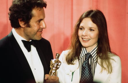 Miloš Forman in a tux holding an Oscar, Diane Keaton in white blazer, polka dot green tie and striped shirt.